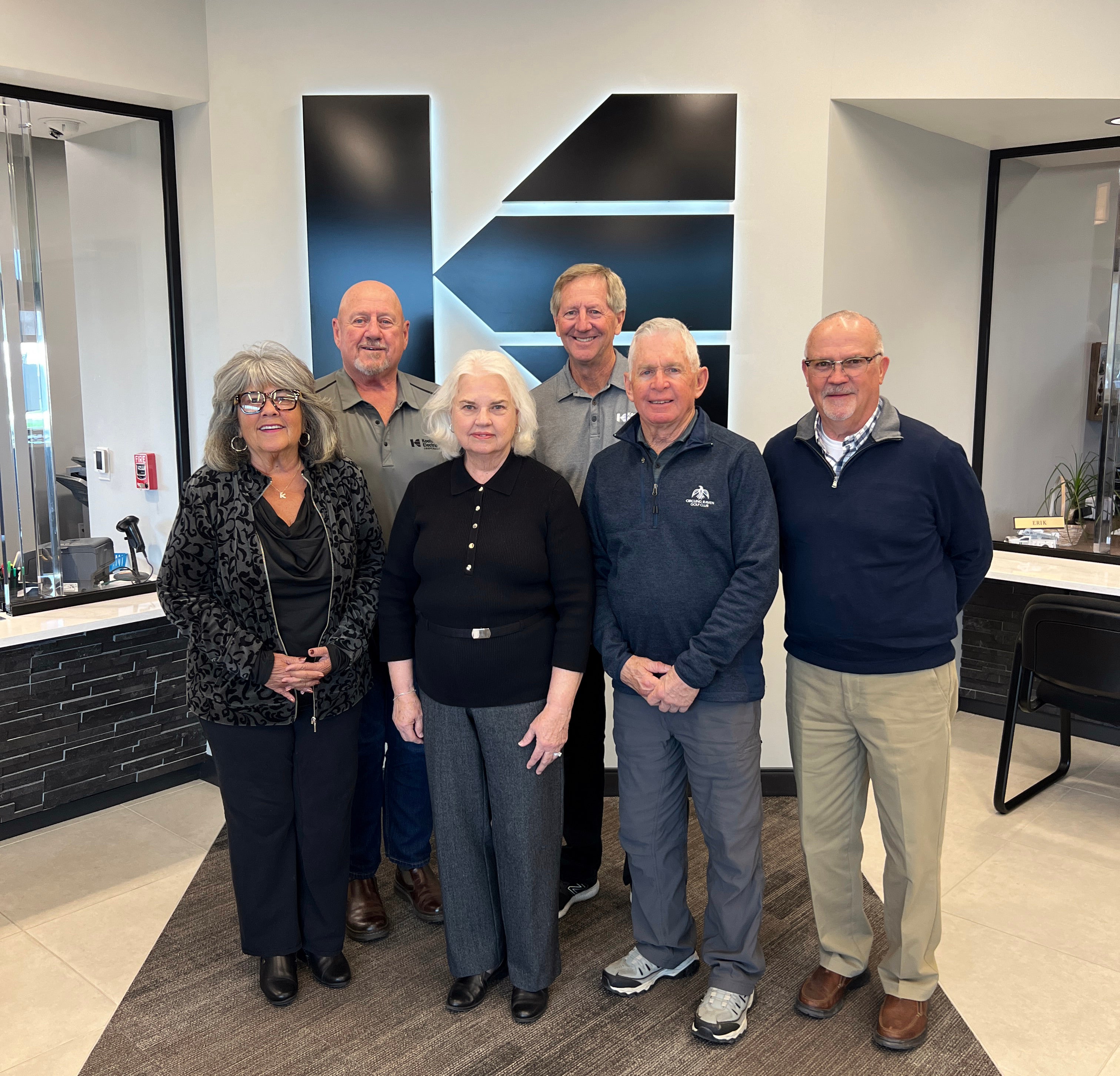 The 2024 Kootenai Electric Trust board members stand in front of the KEC logo in the headquarters lobby.